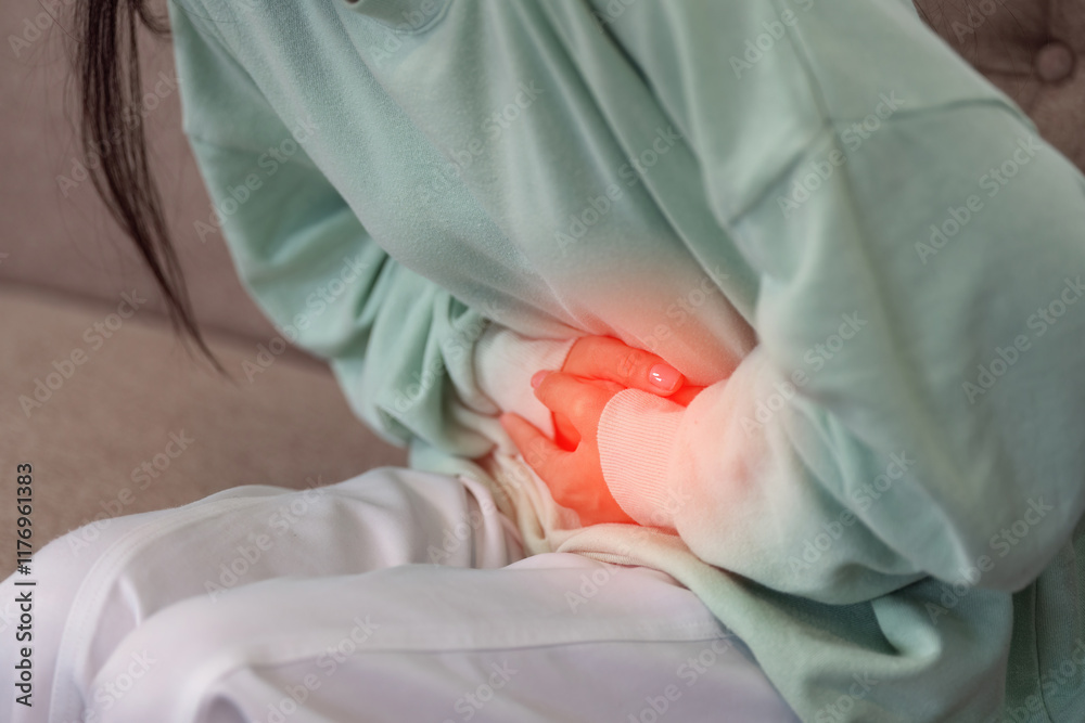 Fototapeta premium Person Experiencing Stomach Pain at Home Highlighting Health and Wellness Concerns in a Domestic Setting