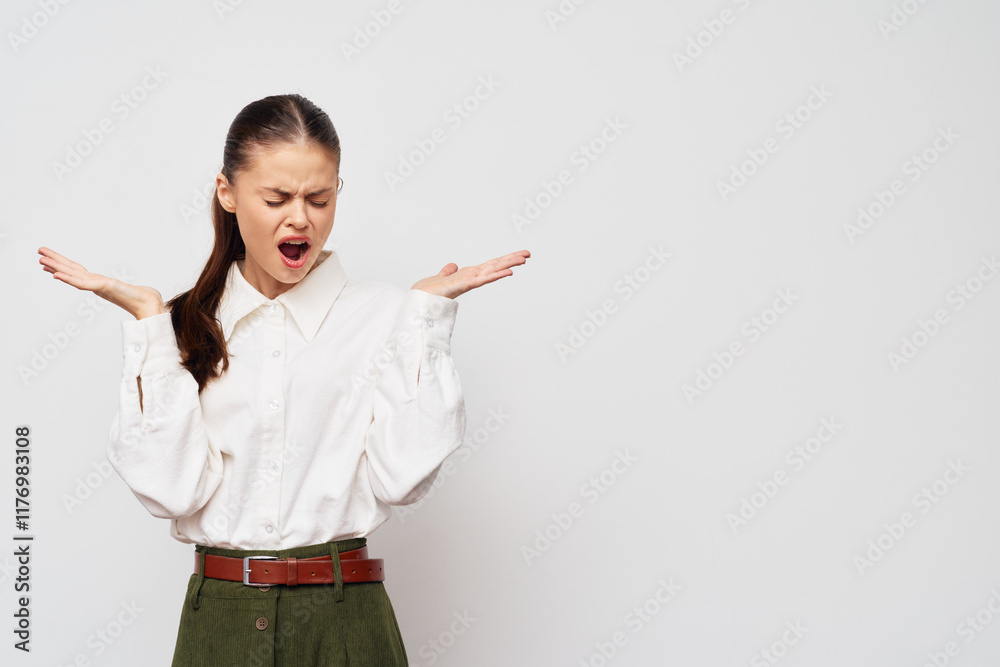 frustrated young girl expressing emotions, wearing a white shirt and green pants, against a plain light background, open hands showing surprise or dissatisfaction, indoor setting frustrated young girl expressing emotions, wearing a white shirt and green pants, against a plain light background, open hands showing surprise or dissatisfaction, indoor setting