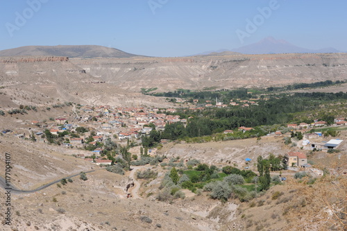 View of the village of Şahinefendi with mountains, rocks and blue sky on a sunny day in summer in the District of Ürgüp, Nevşehir Province, Cappadocia, Turkey