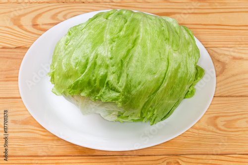 Head of fresh iceberg lettuce on dish on rustic table