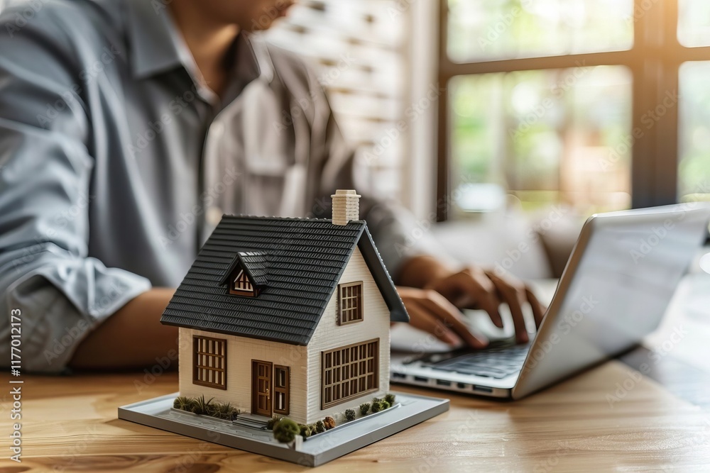 Fototapeta premium House Model in Close Proximity to Laptop on Desk
