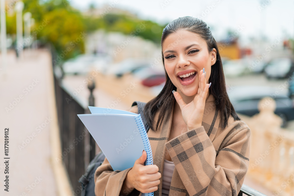 Young pretty student woman at outdoors shouting with mouth wide open Young pretty student woman at outdoors shouting with mouth wide open