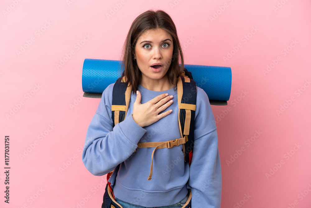 Young mountaineer woman with a big backpack isolated on pink background surprised and shocked while looking right Young mountaineer woman with a big backpack isolated on pink background surprised and shocked while looking right