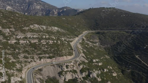 Aerial shot of cars driving on a bucolic road in the Calanques mountains around Marseille, France
