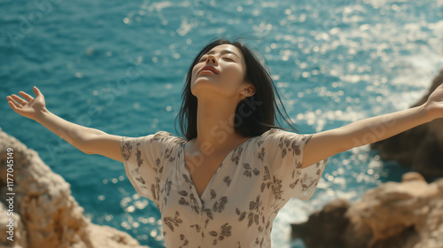 A joyful Asian woman standing by the seaside with her arms outstretched, embodying freedom and happiness while enjoying the refreshing ocean breeze and sunlight. photo