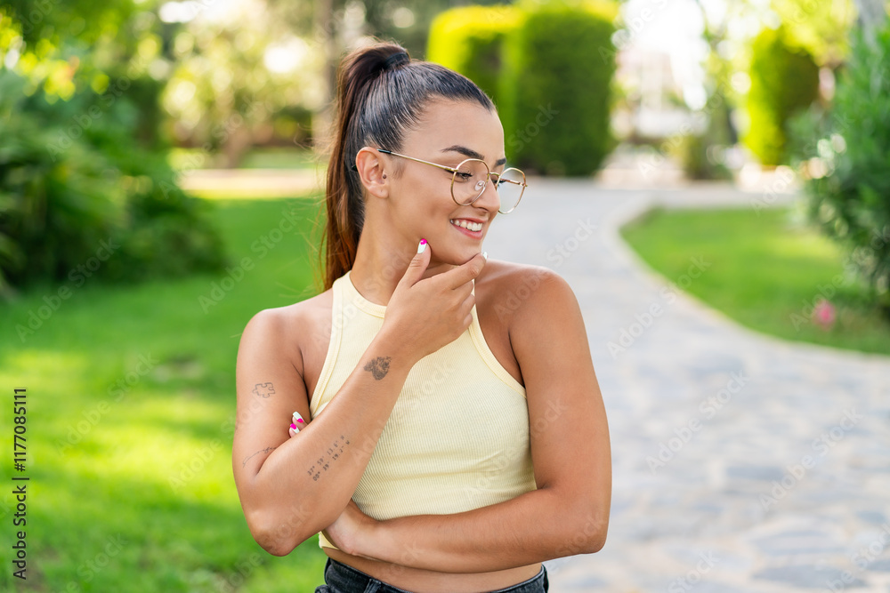 Young pretty woman with glasses at outdoors looking to the side