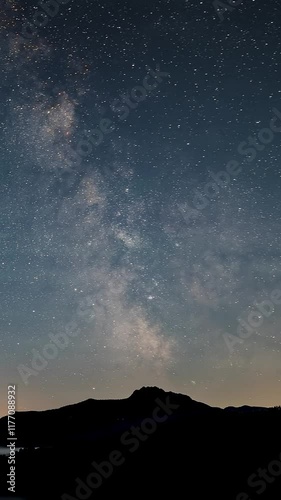 Vertical video of Milky way galaxy stars moving over mountains in summer night to day Time lapse