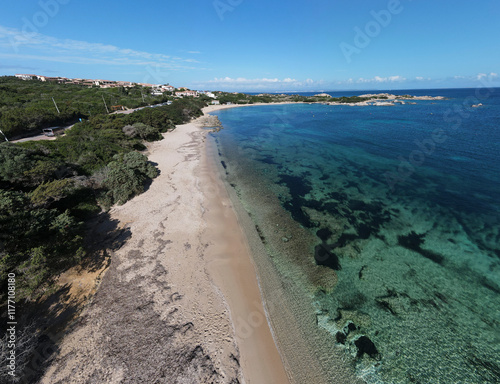 The Rena di Levante beach on Capo Testa, Sardinia, with its clear turquoise waters, sandy shore, and lush surroundings under a bright blue sky. photo