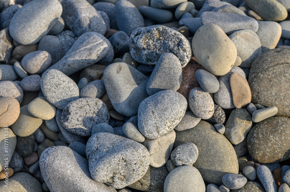 Smooth stones scattered on a tranquil beach creating a natural mosaic of textures and colors Smooth stones scattered on a tranquil beach creating a natural mosaic of textures and colors