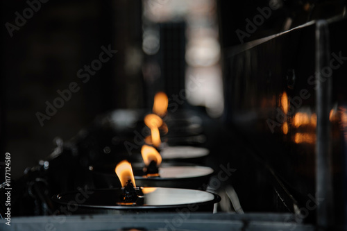 many candles in oil plate light up for people to offering or pray to buddha in Thai's temple photo