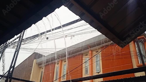Heavy Rain Drops Falling From Roof.Rain flows from a house roof into a gutter during rain. close-up