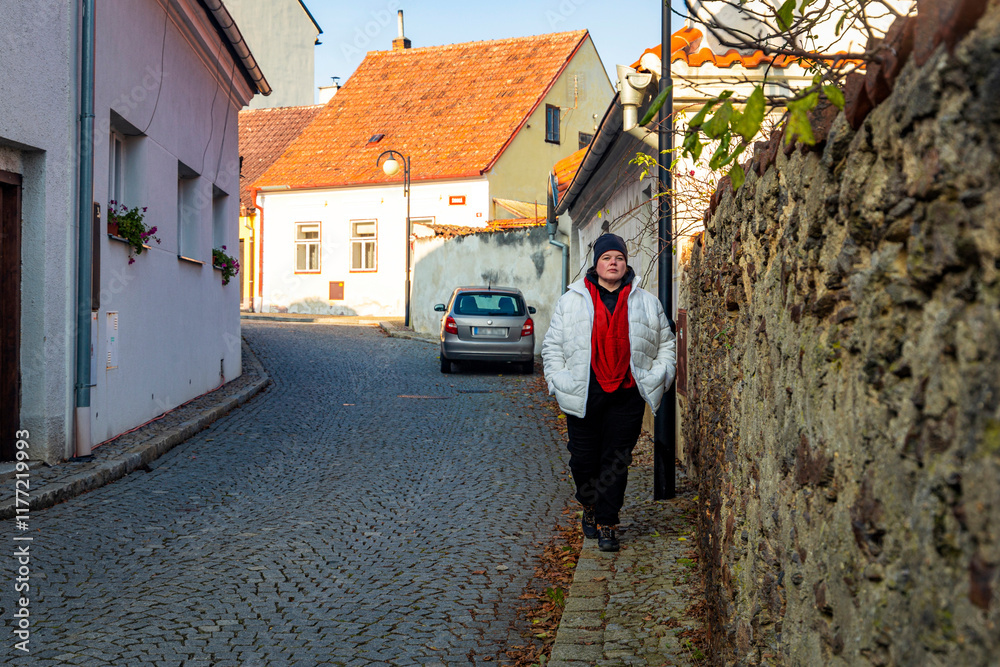 A plus-size woman strolling through the streets of a small European town.