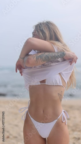 A woman in a white bikini enjoys a sunny beach day, embracing freedom