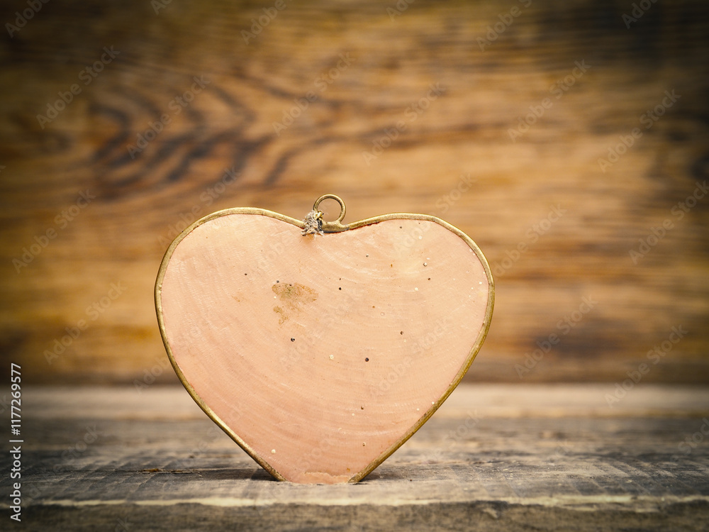 Fototapeta premium Close up of a red metal heart on a rustic wooden table with space for text