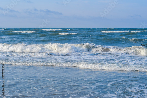 Sea waves rolling on a sandy beach. Close-up of the ocean near the coast. Background on the theme of tourism and family vacation by the water. photo