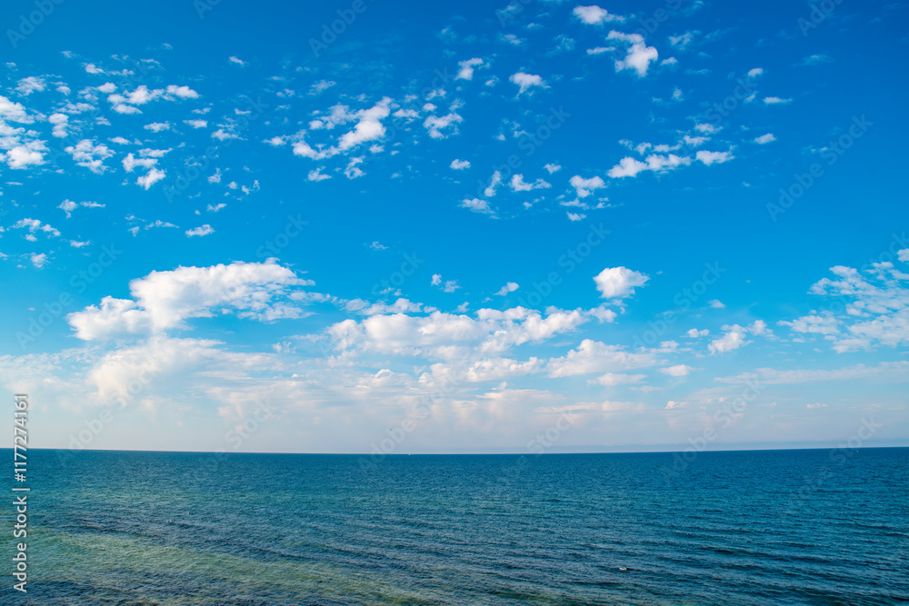 Obraz premium Blue sky with clouds over the sea. Calm landscape on the theme of travel and seaside recreation.