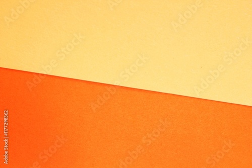 Minimalist abstract background a diagonal split between orange and soft yellow. Close-up of a colorful paper texture with a diagonal line dividing two tones. Concept of simplicity, balance and harmony