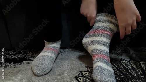 Girl putting warm socks at home. Heating season concept