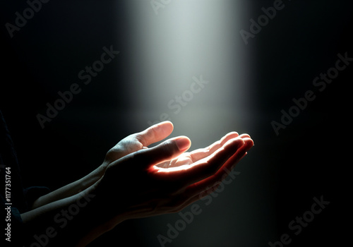 Open hands receiving light in dark environment, symbolizing spirituality, hope, and divine connection