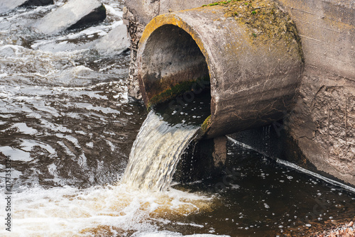 Dirty water flows from the pipe into the river, environmental pollution. Sewerage, treatment facilities
