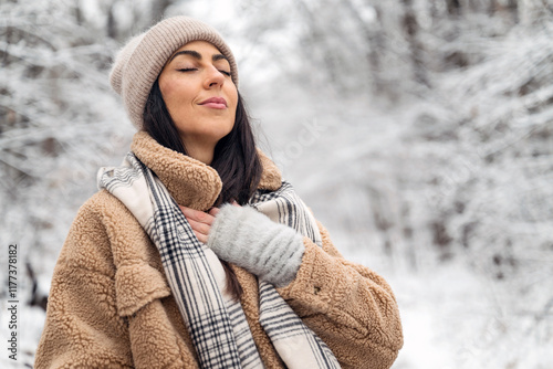 Beautiful  woman breathing fresh air in a snowy forest. Winter time