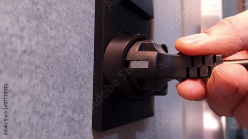 Hand inserts cord with plug from the electrical device to the socket. Electricity, power supply, technology concepts
