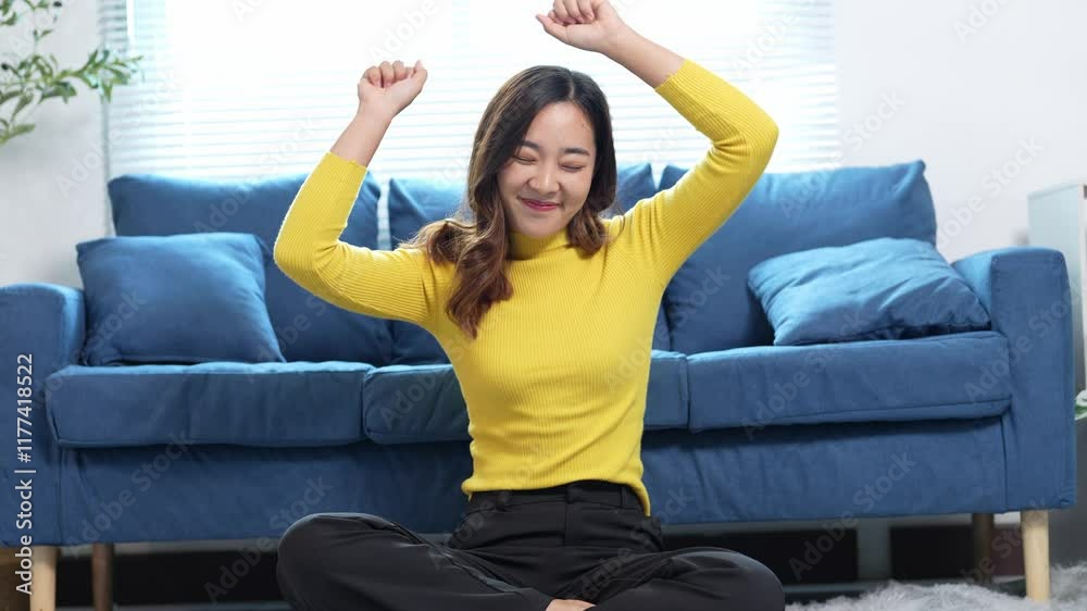 A woman in a yellow shirt is sitting on the floor in front of a blue couch. She is smiling and she is happy A woman in a yellow shirt is sitting on the floor in front of a blue couch. She is smiling and she is happy
