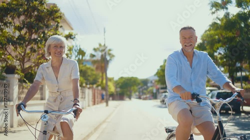 Beautiful happy senior couple dating at the seaside during summertime - Mature married couple in love bonding outdoors and riding bicycle, concepts about elderly lifestyle, transportation and quality