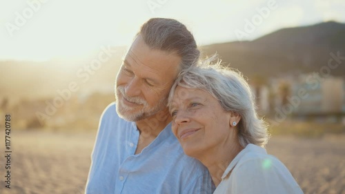 Beautiful happy senior couple dating at the seaside during summertime - Mature married couple in love bonding outdoors at the beach, concepts about elderly lifestyle, relationship and quality of life
