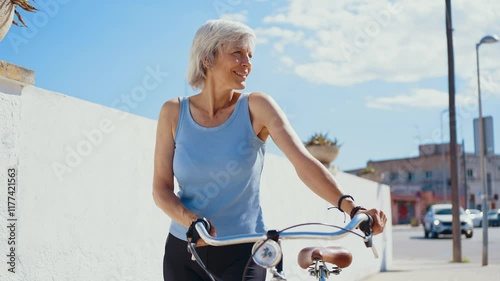 Beautiful happy senior woman cycling during summertime - Mature adult female with gray hair riding bicycle, concepts about elderly lifestyle, transportation and quality of life	