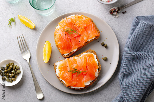 Sandwich, toast with smoked salmon and cream cheese on plate. Grey background. Close up. Top view.