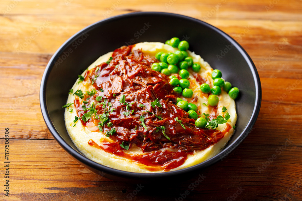 Mashed potatoes with beef meat and green peas in bowl. Wooden background. Close up. Mashed potatoes with beef meat and green peas in bowl. Wooden background. Close up.