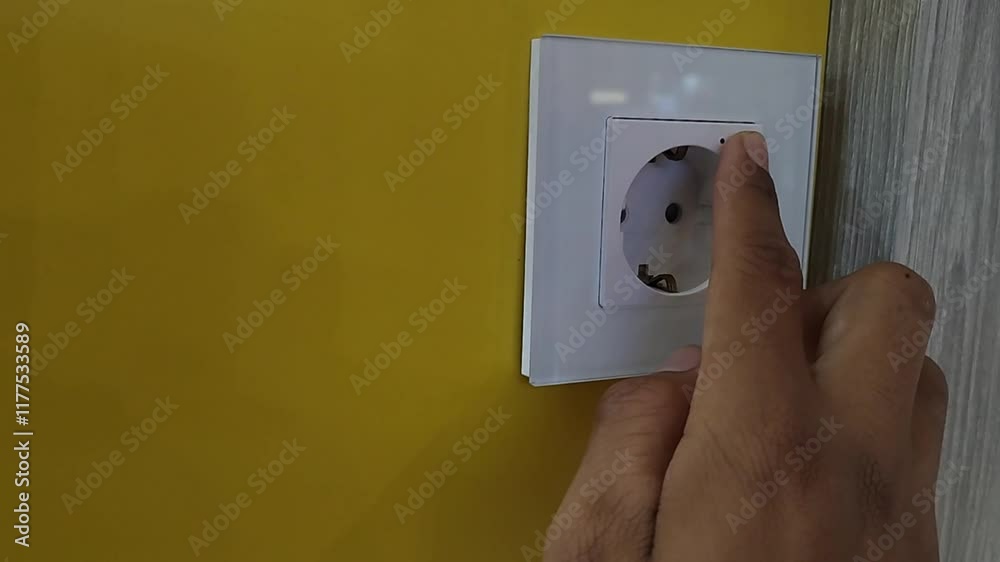 Someone presses the on-off button on an electrical outlet Someone presses the on-off button on an electrical outlet