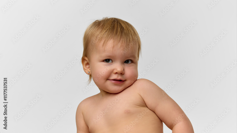 Portrait of a cute baby girl, toddler with blonde hair smiling and looking at camera against studio background. Concept of childhood, health, care, parenthood Portrait of a cute baby girl, toddler with blonde hair smiling and looking at camera against studio background. Concept of childhood, health, care, parenthood
