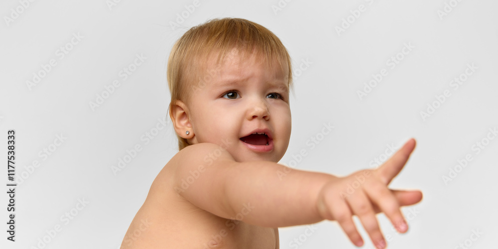 A curious baby girl, toddler spreading hand with interest against studio background. Playful baby. Concept of childhood, health, care, parenthood A curious baby girl, toddler spreading hand with interest against studio background. Playful baby. Concept of childhood, health, care, parenthood