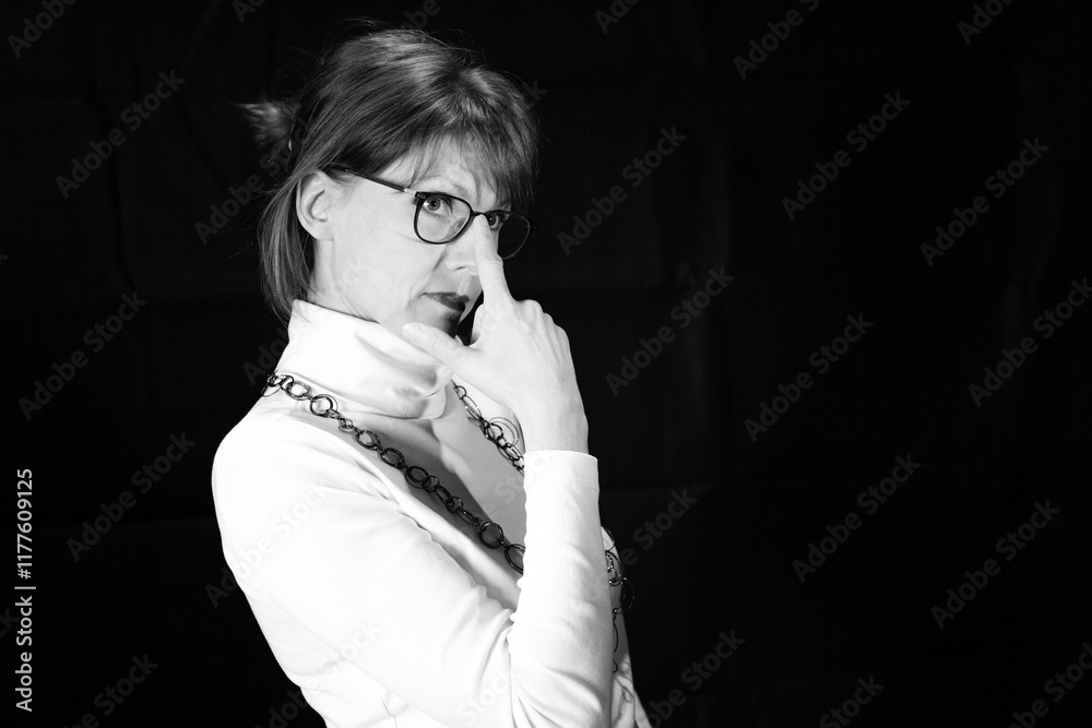 Fototapeta premium Frau mit Brille berührt Gesicht als nachdenkliches Schwarzweißporträt
