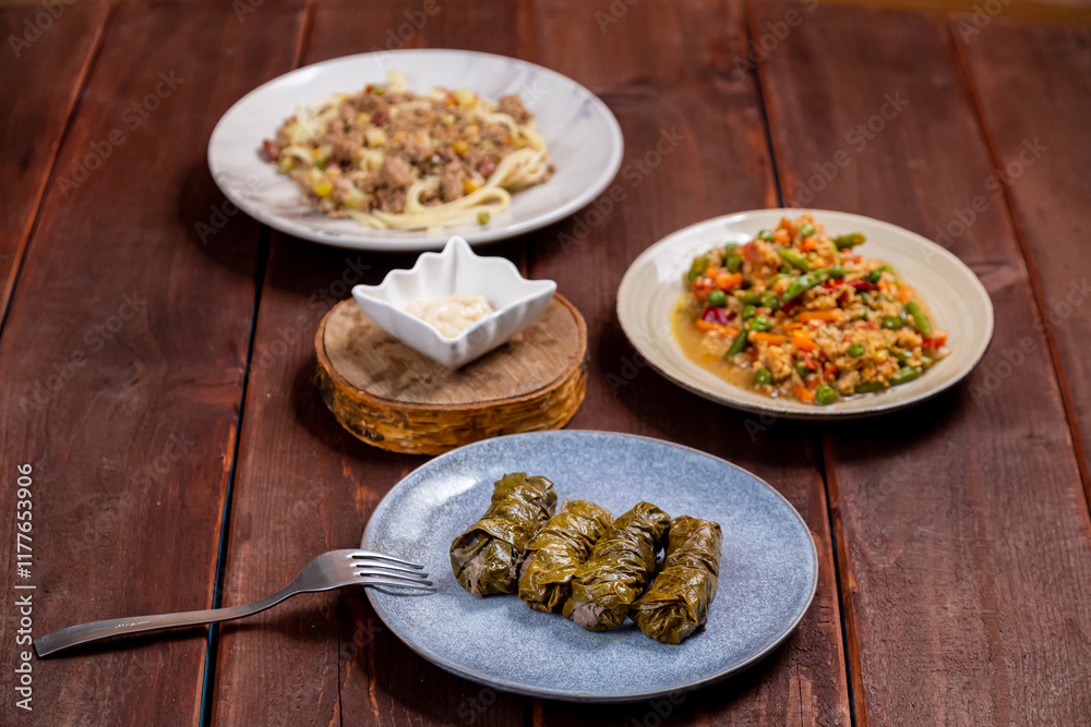 Couscous with vegetables, udon noodles with meat and homemade dolma on a wooden table Couscous with vegetables, udon noodles with meat and homemade dolma on a wooden table