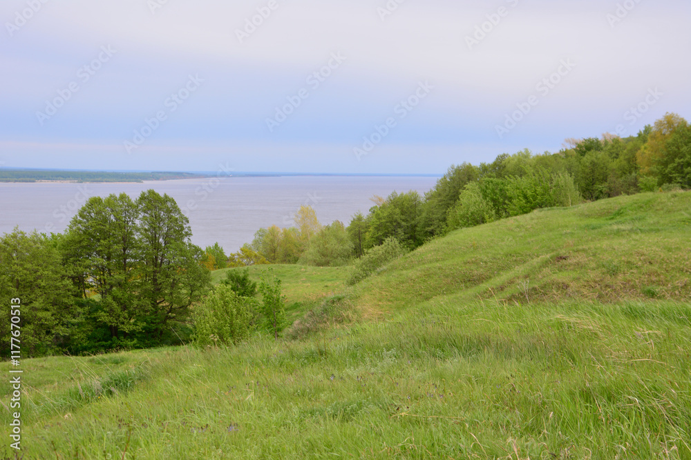 Obraz premium green hills with the river and cloudy sky in the background 
