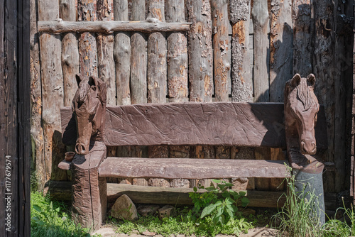 Rustic wooden bench featuring intricately carved horse heads on both sides. Countryside themes photo