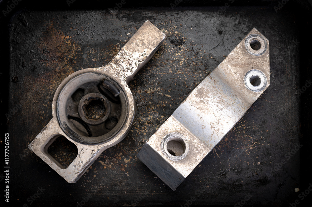 Two worn metal car suspension parts on a textured, rusty surface. Industrial setting showcasing aged mechanical components, perfect for automotive or engineering themes