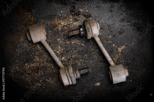 Φωτογραφία Two worn-out car stabilizer links on a textured rusty surface