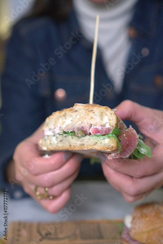 A detailed close-up of a gourmet sandwich being held in both hands. 