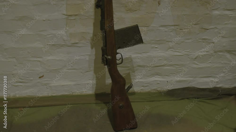 An old rifle with a wooden stock and rusted magazine rests against a ...
