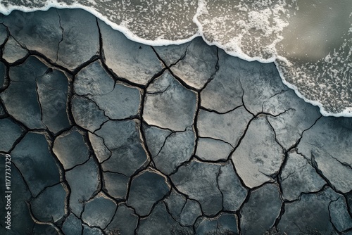 Ocean waves meet cracked, dry earth; a stark contrast of nature's elements. photo