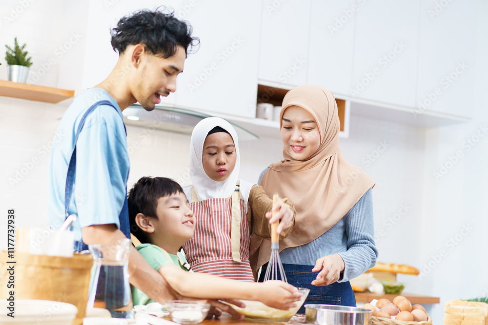 Happy Asian muslim family consisting father, mother, son, and daughter are cooking together in the kitchen. Happy Asian muslim family consisting father, mother, son, and daughter are cooking together in the kitchen.