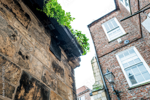 Abstract, wide angle view of a narrow alleyway in the historic medieval town of York, UK. Weeds can be seen growing in the righty iron gutters. photo