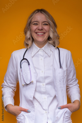 Smiling female doctor in a white lab coat with a stethoscope, standing confidently against a vibrant yellow background, conveying positivity, professionalism, and healthcare expertise. photo