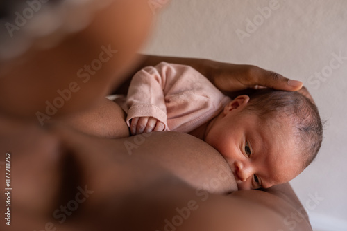 Caring mother holding baby head while nursing photo