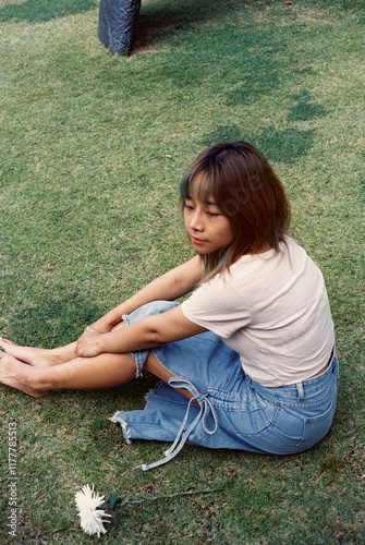 Girl sitting on green yard. Side view portrait. Hi-res film scan