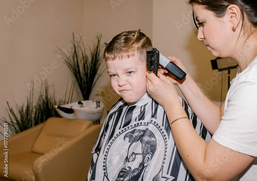 The boy is squirming while the barber cuts his hair. photo